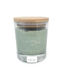 Bougie artisanale corse couleur verte dans un contenant en verre avec un bouchon en bambou couleur marron avec une étiquette blanche ou il est écrit machja.
