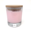 Bougie artisanale corse couleur rose dans un contenant en verre avec un bouchon en bambou couleur marron avec une étiquette blanche ou il est écrit ficu.